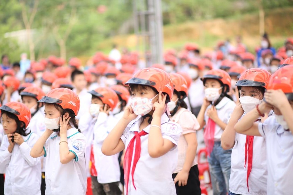 Học sinh tiểu học thực hành đội mũ bảo hiểm đúng quy cách. (Ảnh: Cộng tác viên/Việt Nam+)